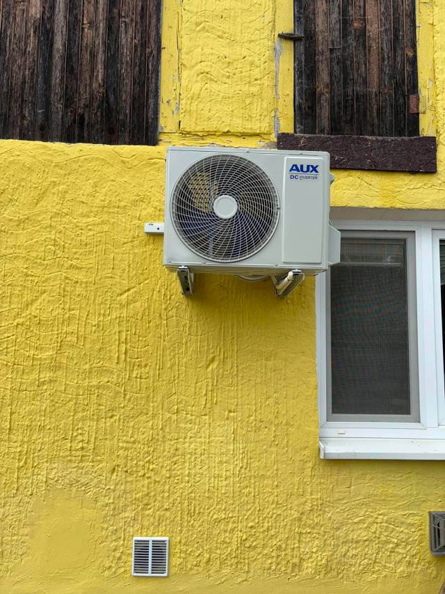Vonkajšia jednotka AUX DC Inverter na žltej fasáde